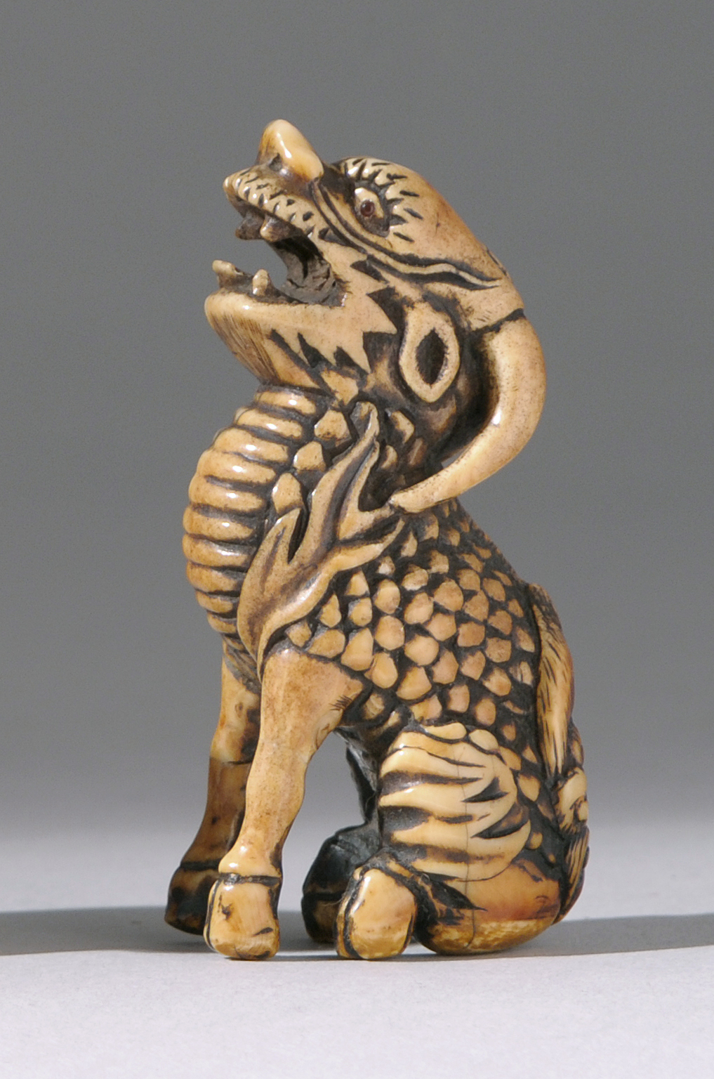 Appraisal: STAGHORN NETSUKE th CenturyDepicting a baying kirin with inlaid eyes