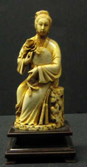 Appraisal: CHINESE CARVED AND STAINED IVORY FIGURE Seated beauty holding a