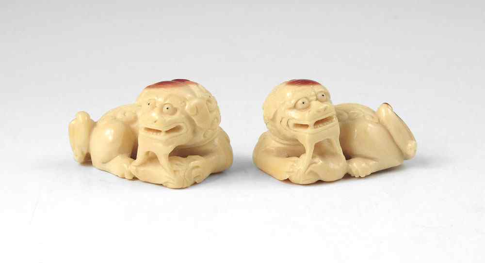 Appraisal: PAIR OF IVORY FOO LION NETSUKES With red highlights signed