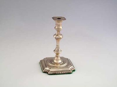 Appraisal: An Edwardian taperstick on a square base with incurved corners