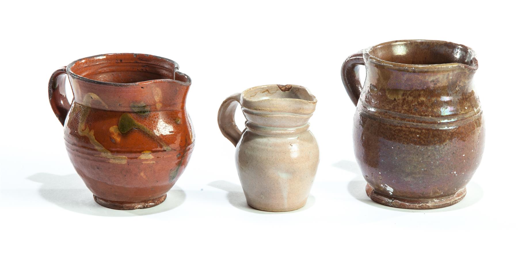 Appraisal: THREE AMERICAN REDWARE CREAMERS Nineteenth century Bristol-type glaze green accents