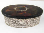 Appraisal: An embossed oval jewellery box with silver inlaid tortoiseshell lid