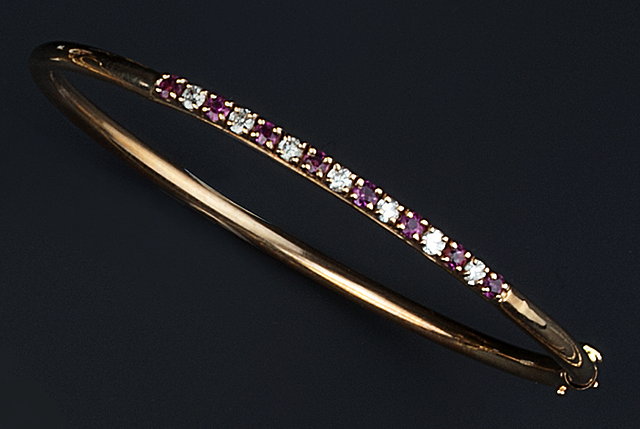 Appraisal: A RUBY AND DIAMOND SET BANGLE of hinged oval form