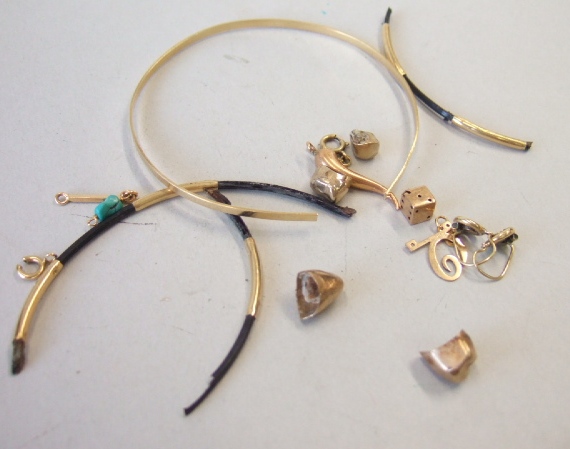 Appraisal: A gold bangle cut another bangle three charms and drops