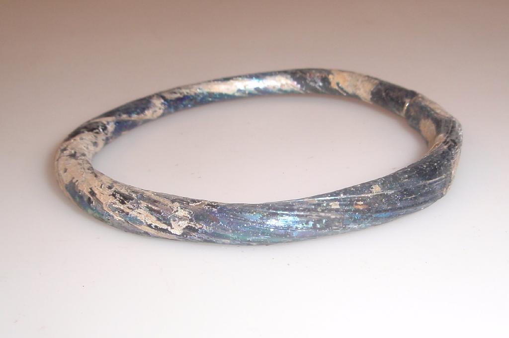 Appraisal: A twisted Byzantine glass bangle appearing black and partly covered