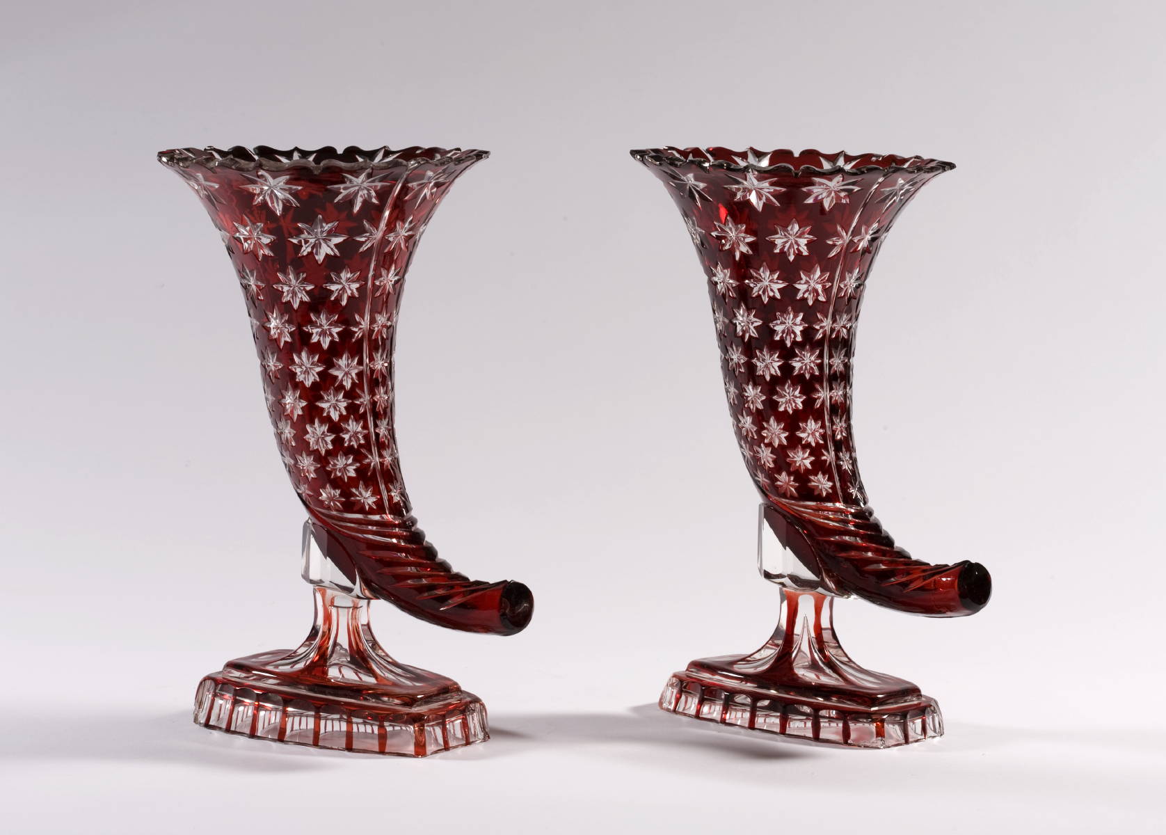 Appraisal: PAIR OF BOHEMIAN RED-FLASHED CORNUCOPIA-FORM VASES WITH STAR MOTIF Height