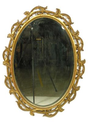 Appraisal: An oval giltwood wall mirror with a bevelled plate and