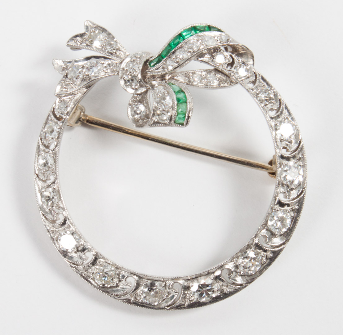 Appraisal: Diamond and emerald bow-ring brooch in W unmarked K white