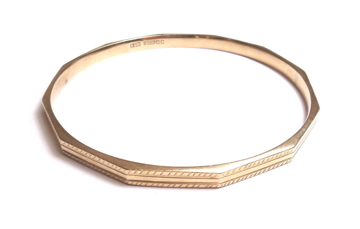 Appraisal: A ct gold faceted circular bangle with engine turned decoration