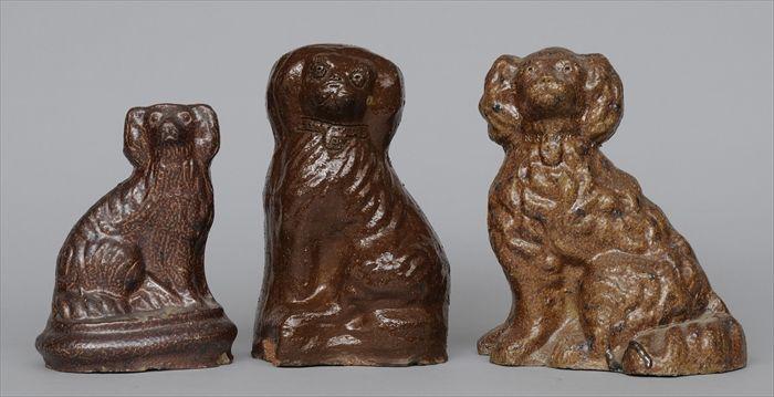 Appraisal: THREE SEWER TILE SPANIEL FIGURES Each modeled seated tallest in