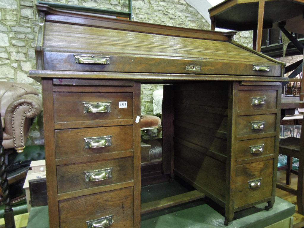 Appraisal: An Edwardian oak roll top kneehole pedestal desk the sloped