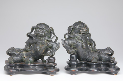 Appraisal: ASIAN BRONZE Pair of Buddhistic lions with fierce expressions holding