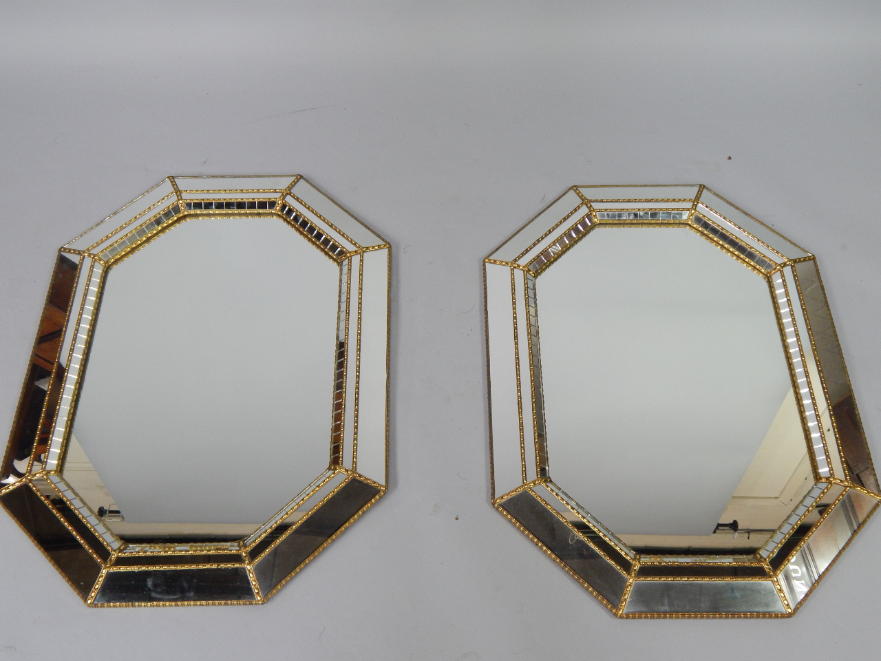 Appraisal: A pair of brass and glass panelled octagonal wall mirrors