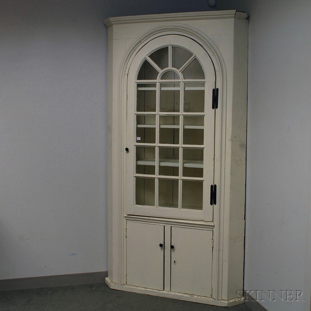 Appraisal: White-painted Glazed Corner Cupboard the flat-molded cornice over an arched