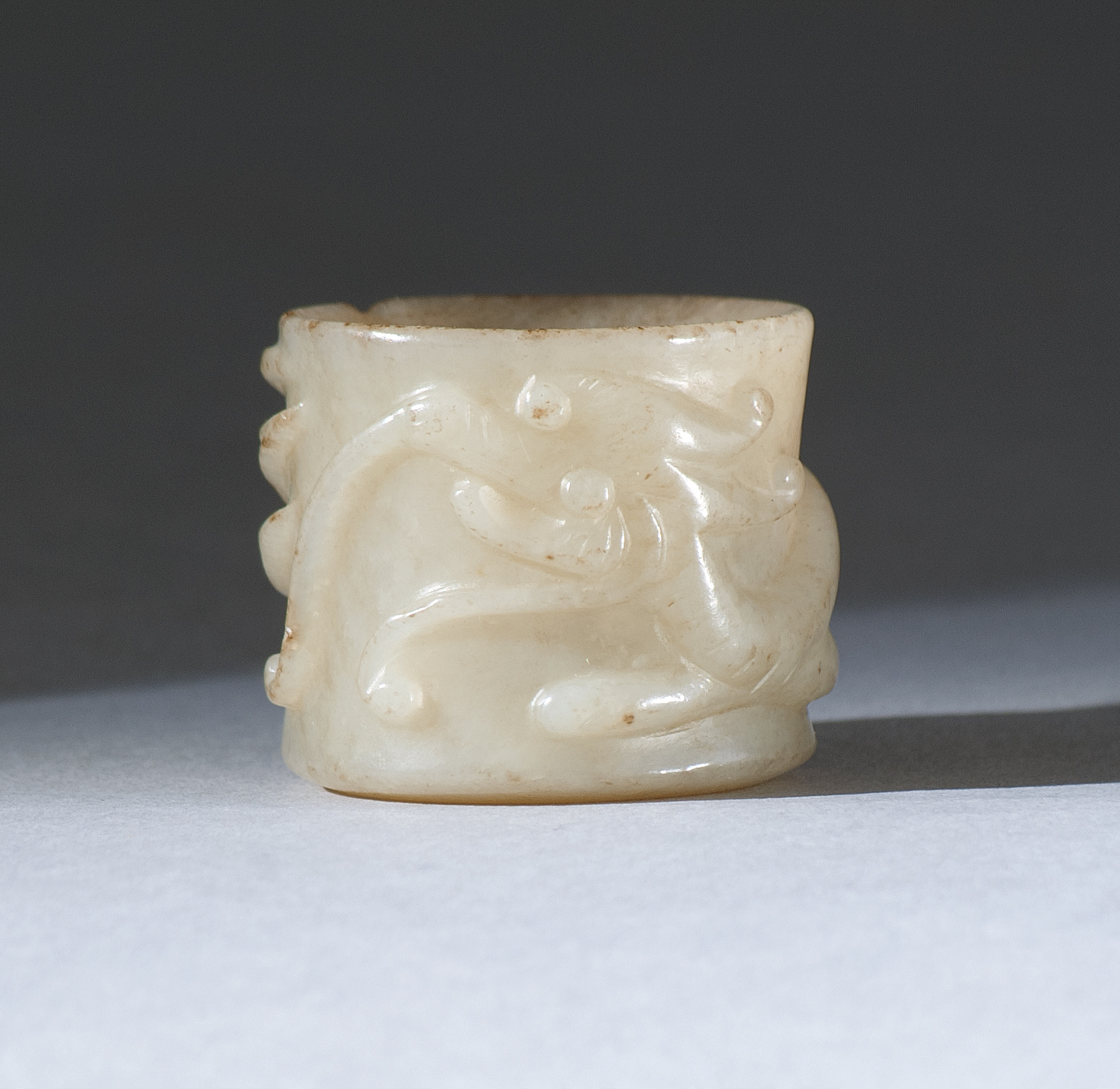 Appraisal: GRAY JADE THUMB RING th CenturyWith high-relief dragon carving From