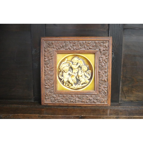 Appraisal: Glazed majolica tile of putti in a well carved frame