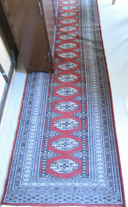 Appraisal: HAND KNOTTED BOKHARA RUNNER red ground ' x '