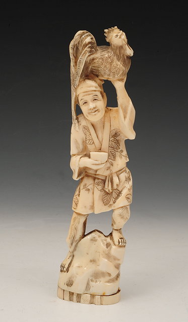 Appraisal: A JAPANESE WALRUS IVORY CARVED OKIMONO a figure holding a