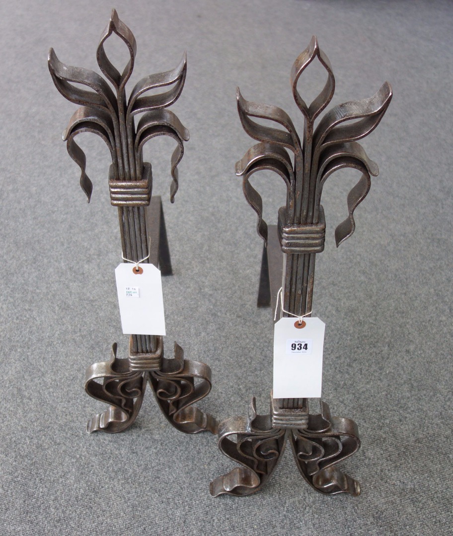 Appraisal: A pair of steel andirons of stylised fleur-de-lys form cm