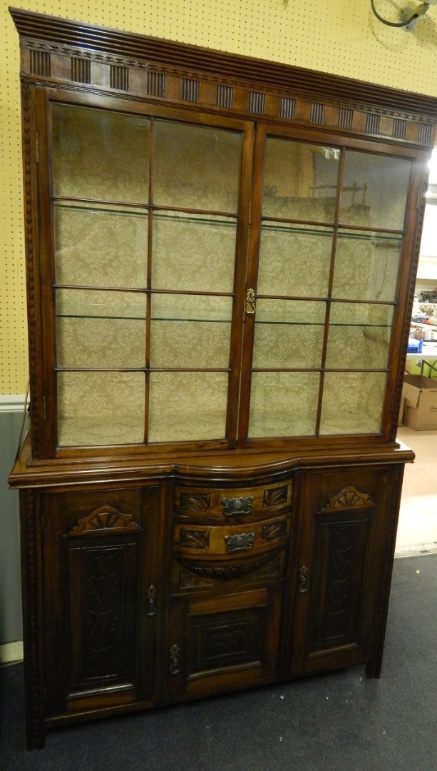 Appraisal: A walnut display cabinet the top with geometric carving and