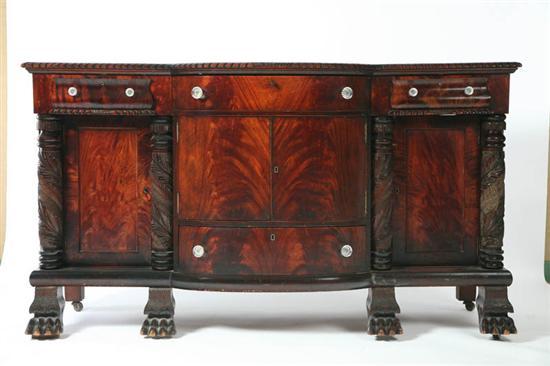 Appraisal: EMPIRE SIDEBOARD Flame grain mahogany veneer serpentine front carved columns