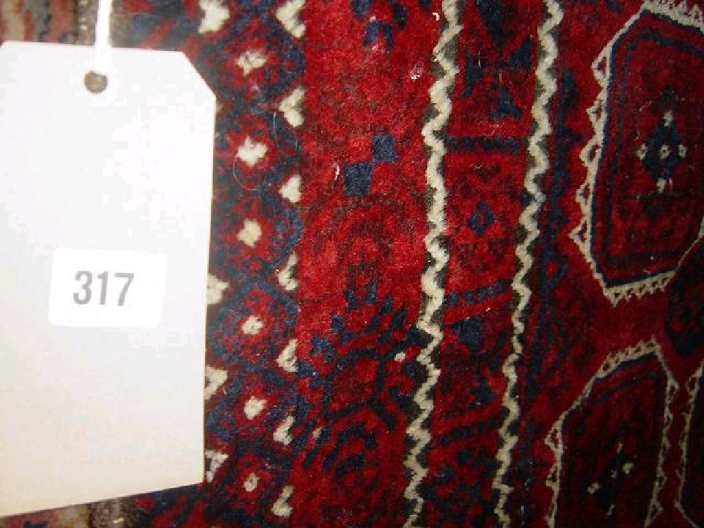 Appraisal: A red ground wool rug with repeating gul decoration in