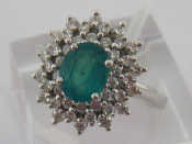 Appraisal: An emerald and diamond cluster ring the central oval cut