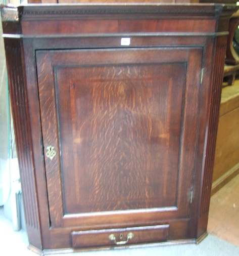 Appraisal: A George III oak hanging corner cupboard with a dentil