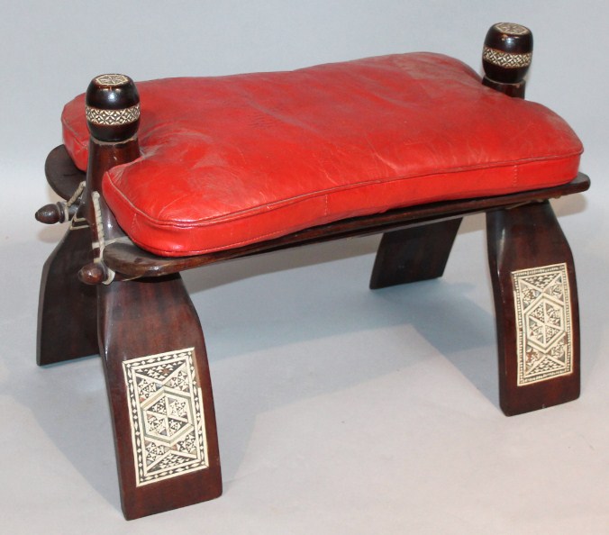 Appraisal: A thC camel stool with red leatherette top surmounted by