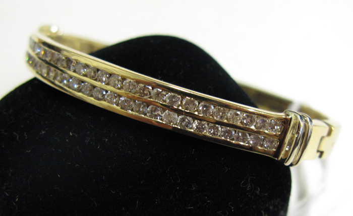 Appraisal: DIAMOND AND FOURTEEN KARAT GOLD BANGLE set with two channels