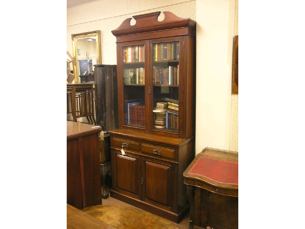 Appraisal: A Victorian walnut bookcase arched pediment above a pair of