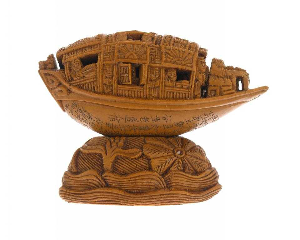 Appraisal: A CHINESE OLIVE STONE CARVING OF A SAMPAN AND STAND