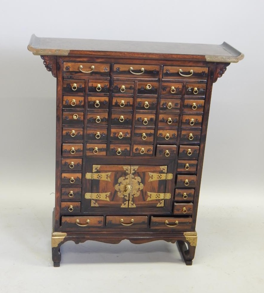 Appraisal: A Chinese hardwood medicine cabinet the overhanging scroll top upheld