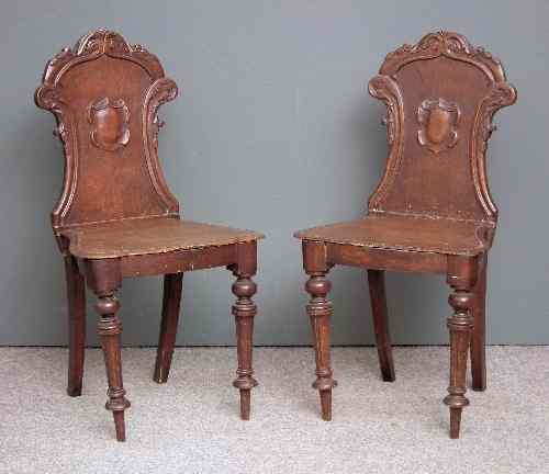 Appraisal: A pair of Victorian oak hall chairs with shaped and