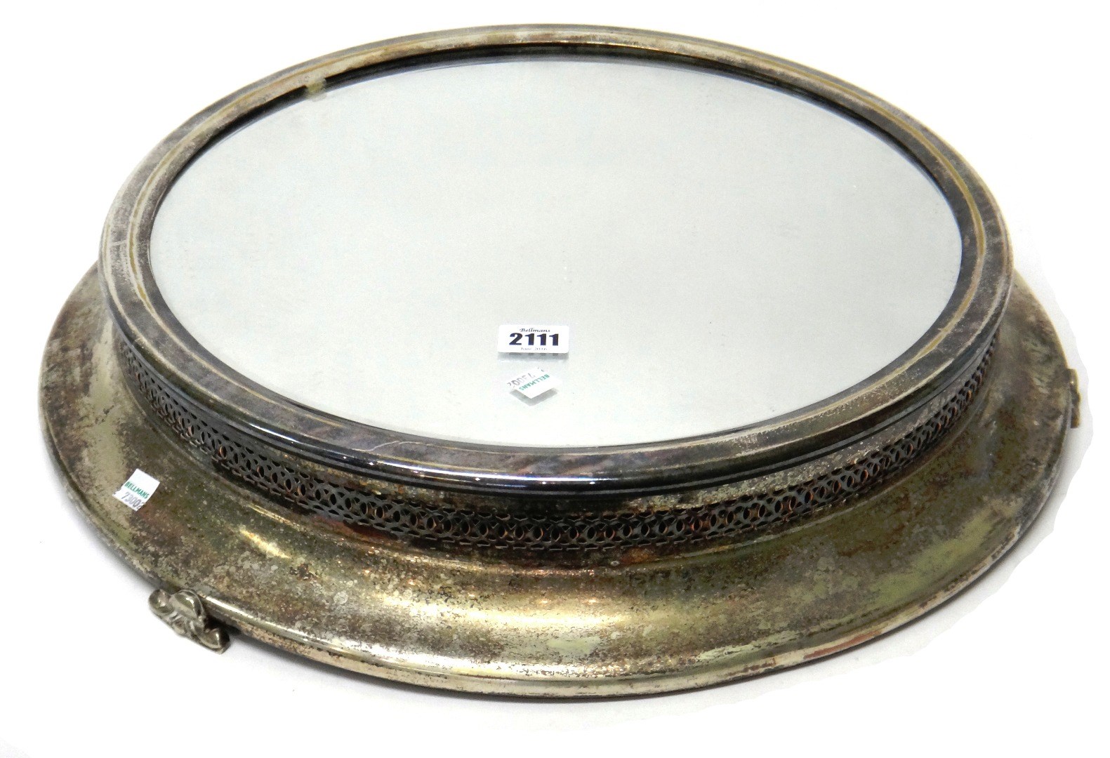 Appraisal: A silver plated metal mounted circular mirror plateau raised on