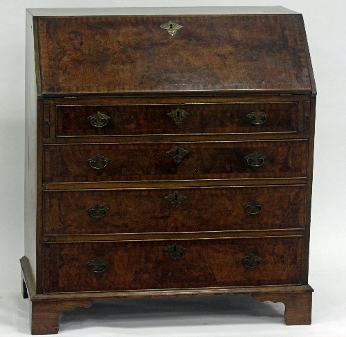 Appraisal: A walnut veneered bureau cross banded fitted beneath the fall