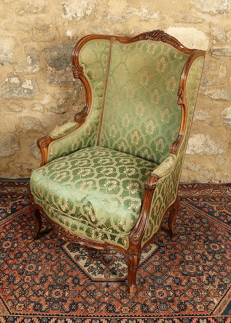 Appraisal: A FRENCH LOUIS XV STYLE WING ARMCHAIR with carved beech