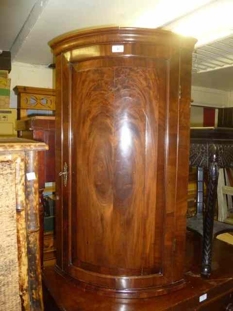 Appraisal: A GEORGIAN MAHOGANY BOW FRONT CORNER CUPBOARD with single panel