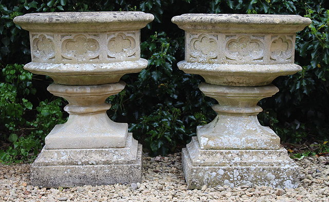 Appraisal: A PAIR OF WEATHERED HADDONSTONE STYLE URNS with square bases