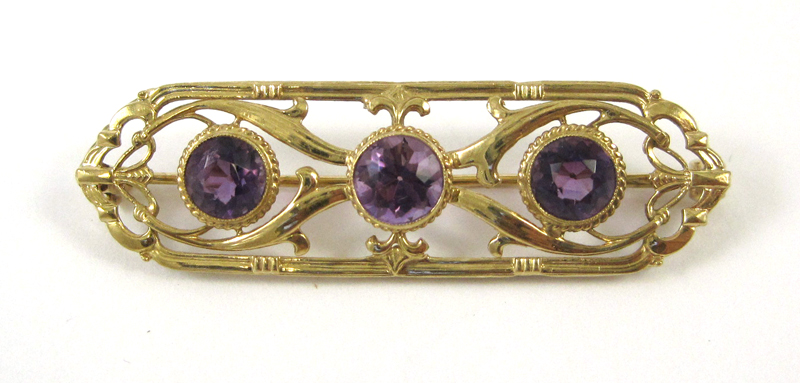 Appraisal: AMETHYST AND FOURTEEN KARAT GOLD BROOCH set with three round-cut