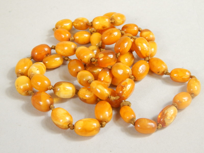 Appraisal: A quantity of polished amber beads on a cord stringing