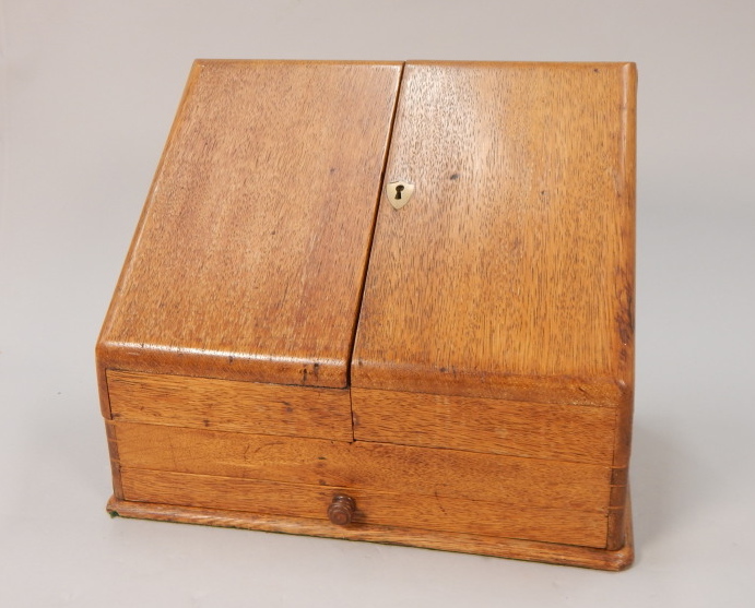 Appraisal: An Edwardian oak stationery box with a slope top enclosing