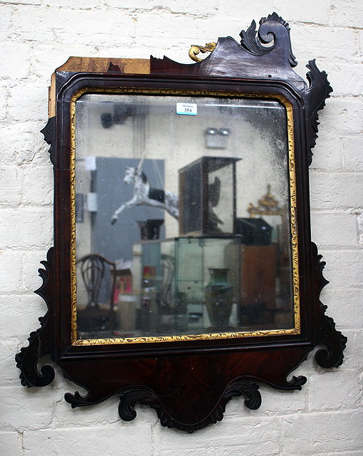 Appraisal: AN ANTIQUE MAHOGANY FRET FRAMED WALL MIRROR with scroll decoration