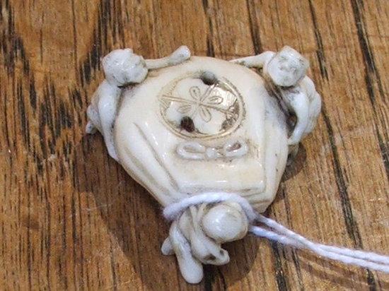 Appraisal: AN IVORY NETSUKE of three figures dragging a sack long