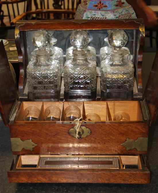 Appraisal: An Edwardian brass mounted oak tantalus with games drawer beneath