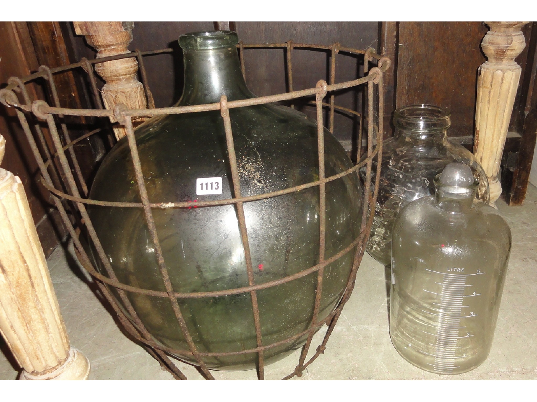 Appraisal: A vintage green glass carboy encased in a wirework basket