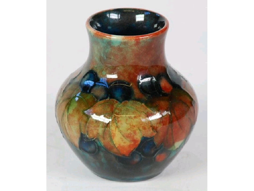 Appraisal: MOORCROFT POTTERY FLAMBE GLAZED SMALL BALUSTER VASE painted with fruiting