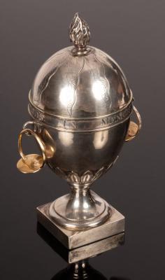 Appraisal: A silver coloured metal egg-shaped urn with flame finial to