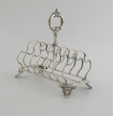 Appraisal: A Victorian six slot toastrack with shaped dividers on scroll