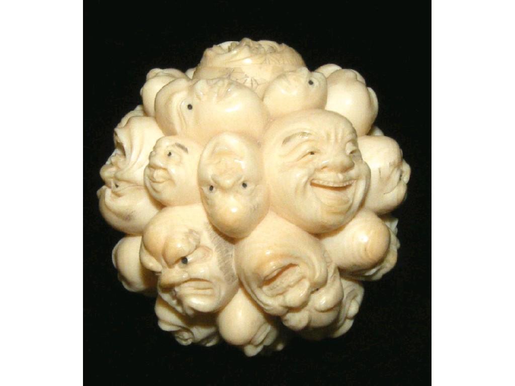 Appraisal: Carved ivory mask ball depicting many heads with smiling facial